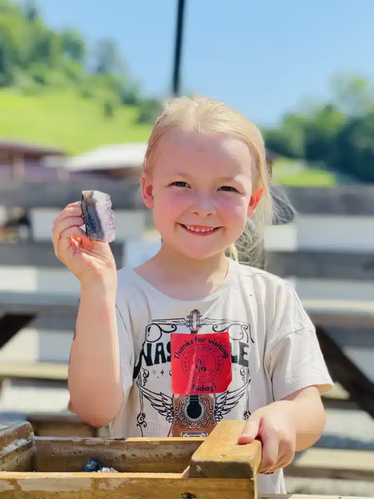 Young visitor holding a gemstone she found at the gem mining sluice on a farm field trip